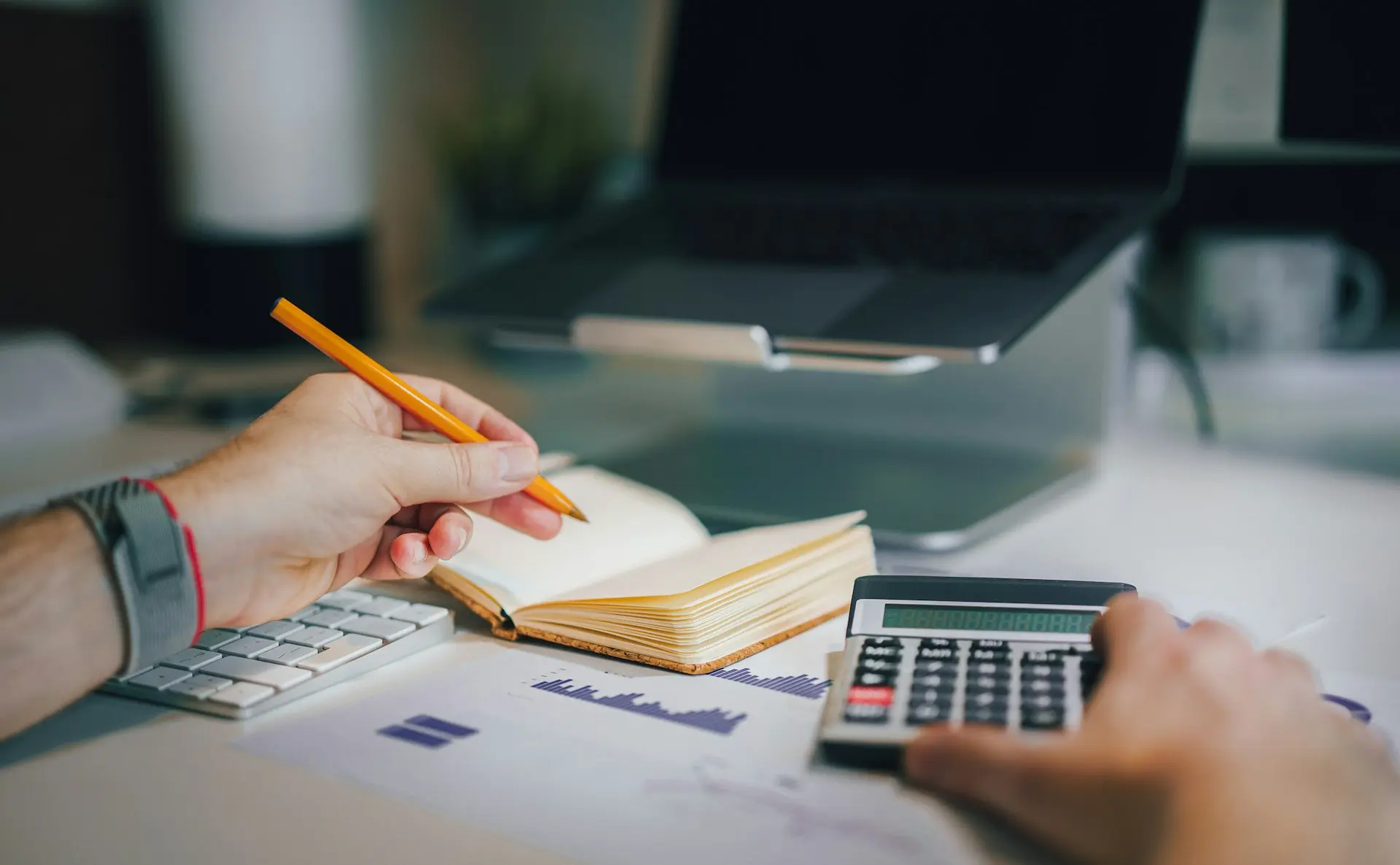 a person sitting at a desk with a calculator and a notebook